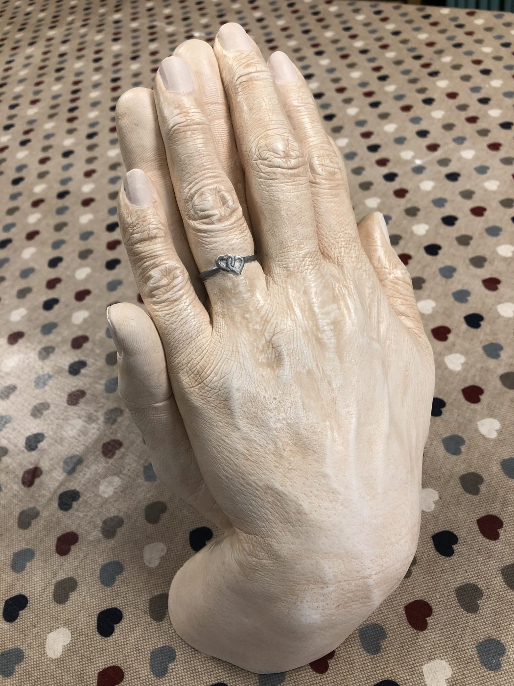 Cast of two adult hands entwined, one wearing a ring