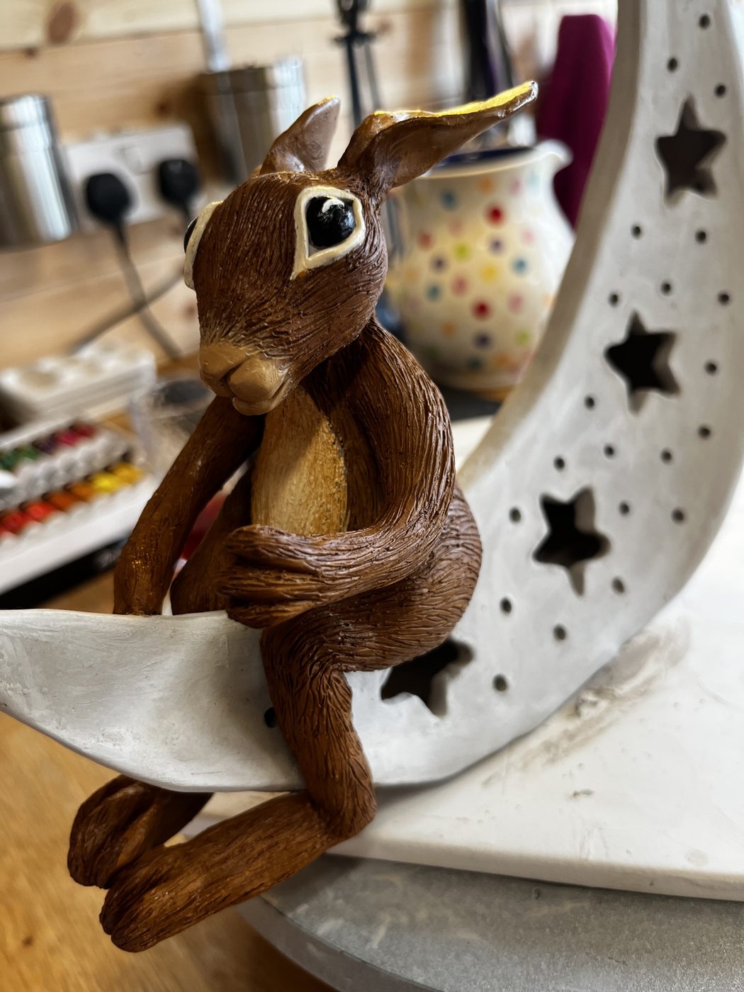 Painted hare sitting on a ceramic moon nightlight with star cut-outs