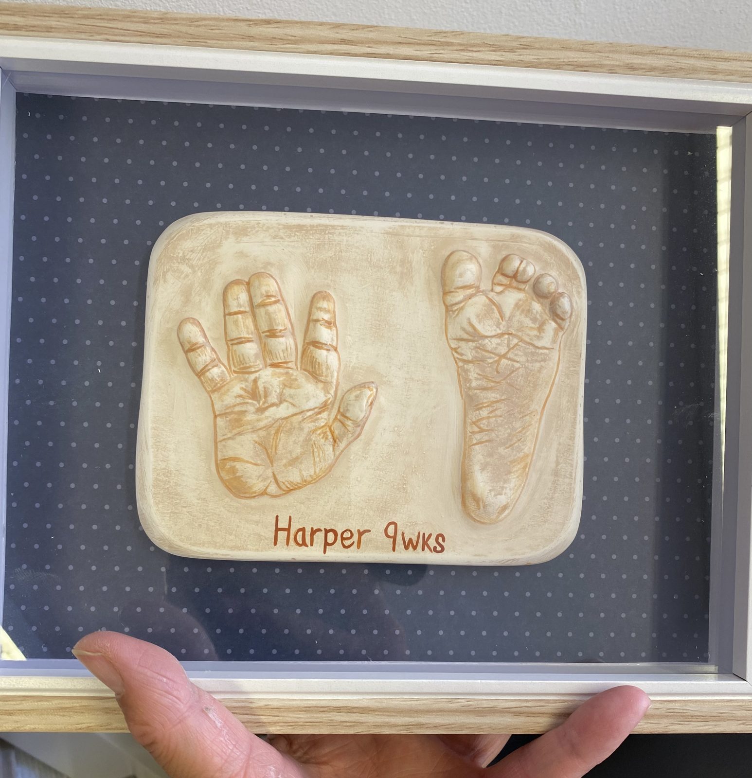 Raised cast of a baby hand and foot in a box frame